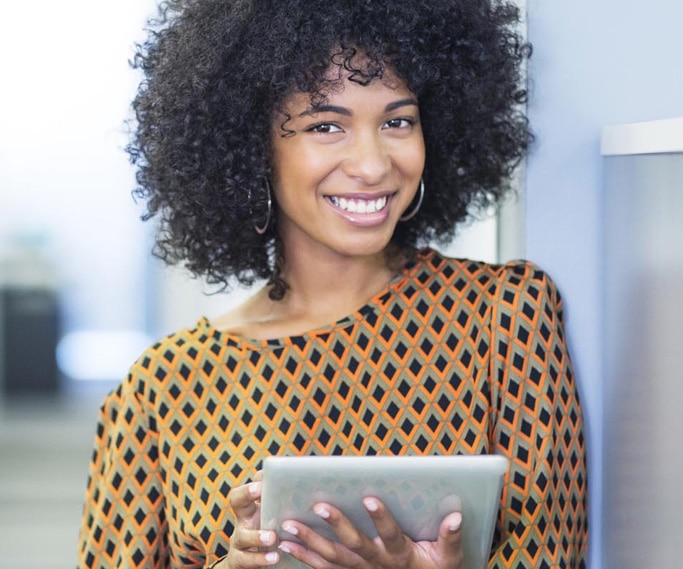 Woman smiling at the camera holding a tablet